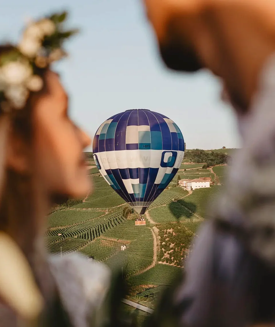 Una pareja contempla un globo aerostático sobre las colinas cubiertas de viñedos