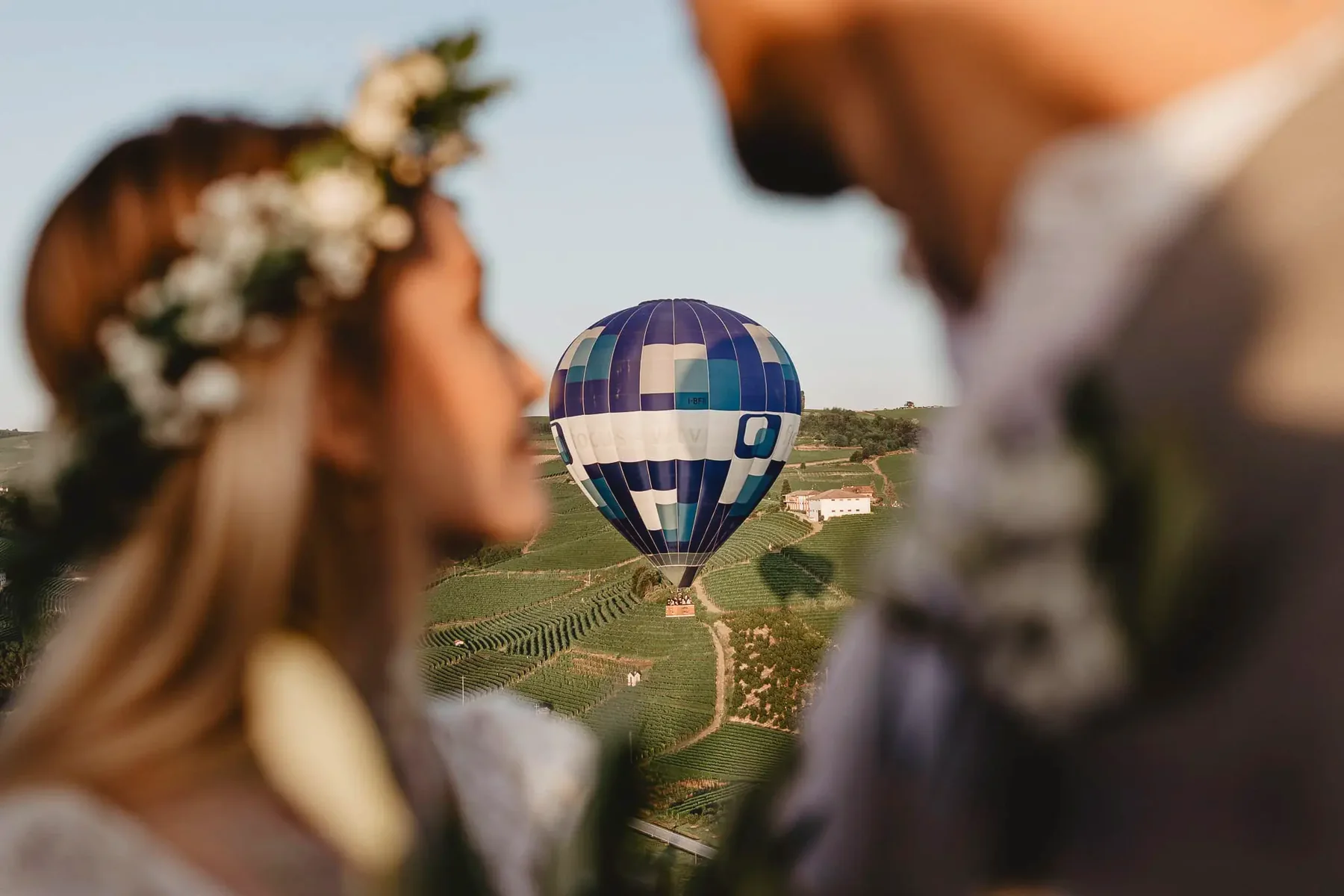 Una pareja en primer plano y un globo sobre los viñedos